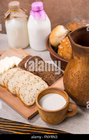 Frische Milch, Vollkornbrot und Käse serviert fein säuberlich auf ein Schneidbrett aus Holz für einen gesunden Snack rustikal Stockfoto