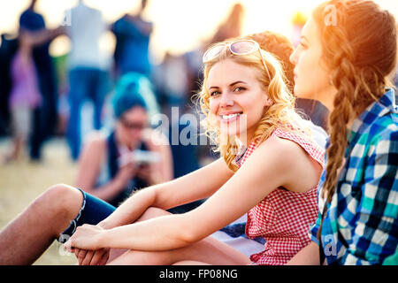 Jugendliche im Sommer-Musikfestival, sitzen auf dem Boden Stockfoto