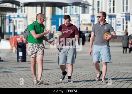 Aberystwyth Wales UK, Mittwoch, 16. März 2016 UK Wetter: drei junge Männer in kurzen Hosen zu Fuß entlang der Promenade genießen die warme Frühlingssonne in Aberystwyth, West Wales UK.  An einem anderen Tag von klarem Himmel und Sonnenschein das die Temperatur erreichte einen Höchststand von 13ºc Credit: Keith Morris/Alamy Live-Nachrichten Stockfoto