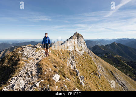 Wanderer zu Fuß auf dem Gipfelgrat des Mount Hochplatte mit dem Panorama der Ammergauer Alpen an einem Herbstmorgen, Bayern, Deutschland Stockfoto