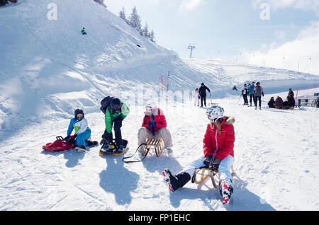 Winterurlaub Alpen; Jugendliche und Kinder Rodeln in den Schweizer Alpen an der Lenk, Kanton Bern, Schweiz, Europa Stockfoto