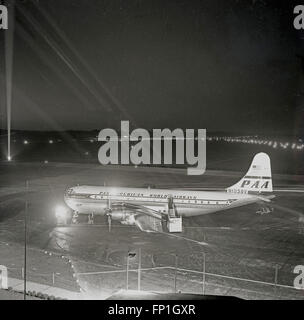 1950er Jahre, historische, Nacht und dem Flughafen Dublin, eine "Pan Am" - Pan American World Airways - Flugzeuge auf der Startbahn wartet. Die Firma war der Erste, der die Boeing 377 Stratocruiser zu betreiben und war der primäre Benutzer. Das Flugzeug war einer der fortschrittlichsten und der Lage der Propeller-driven Transport. Stockfoto