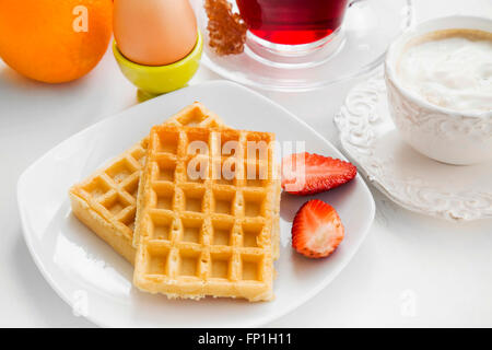 Essen Frühstück mit Waffeln und Erdbeeren, Kaffeetasse und Tee, frisches Obst Stockfoto