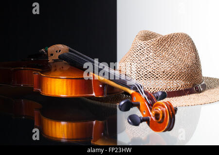 Alte Geige und Strohhut isoliert auf schwarzen und weißen Hintergrund und Glas Schreibtisch Stockfoto