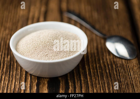 Schale mit Trockenhefe (Tiefenschärfe) auf hölzernen Hintergrund Stockfoto