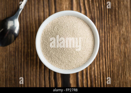 Schale mit Trockenhefe (Tiefenschärfe) auf hölzernen Hintergrund Stockfoto