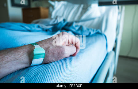 Detail der Arm eines Mannes in einem Krankenhausbett mit Handgelenk-Tag Stockfoto