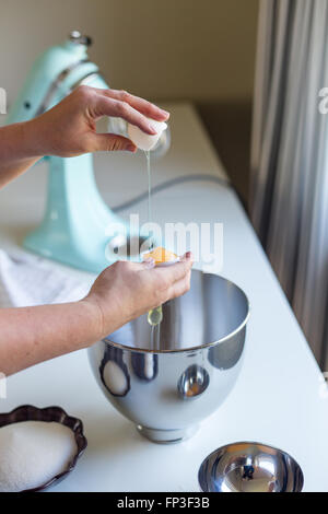 Frau knacken ein Ei in eine Schüssel geben trennen das Eiweiß vom Eigelb Stockfoto