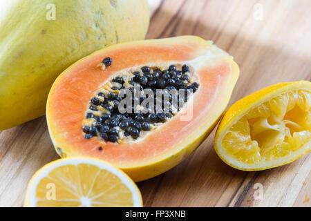 Nahaufnahme von einer Papaya halbieren auf einem Holzbrett serviert mit einer in Scheiben geschnittenen Zitrone Stockfoto