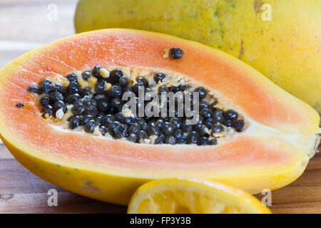 Nahaufnahme von einer Papaya halbieren enthüllt das Fleisch und ein Haufen von dunklen schleimigen Samen Stockfoto