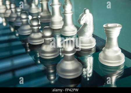 Stücke von einem Glas oder einer harten Kunststoff Schach set Leuchten sind Hintergrundbeleuchtung durch die tiefstehende Sonne durch ein Fenster. Stockfoto