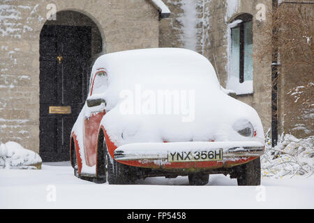 Ein Volkswagen Käfer Oldtimer mit Schnee bedeckt und auf einer Einfahrt in eine häusliche Unterkunft geparkt. Stockfoto