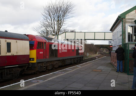 Eine DB Cargo Rail Klasse 60 Diesellok schleppt einen Personenzug der Charta durch Plattform 4 Helsby Station in Cheshire. Stockfoto