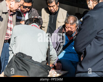 Senioren Herren ein Spiel des Xiangqi, oder chinesisches Schach, genau beobachtet von anderen in den beliebten Tempel des Himmels Park Stockfoto