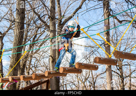 Junge mit Kletterausrüstung während der Passage der Hindernisse Kurs Stockfoto