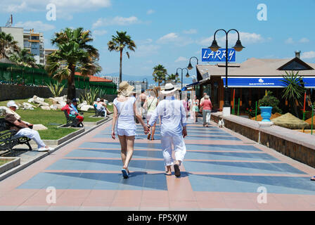 Touristen zu Fuß entlang der Promenade mit Strand-Bars an der rechten Seite, Benalmadena, Costa Del Sol, Provinz Malaga, Spanien. Stockfoto