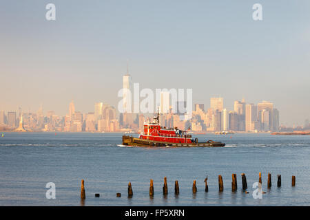 Lower Manhattan New York Skyline mit einem Schlepper und Financial District Wolkenkratzer (World Trade Center) und Statue of Liberty Stockfoto