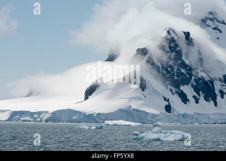 Kalbende Gletscher und Wolken über der Küste von Paradise Bay, antarktische Halbinsel. Paradies Harbor, auch bekannt als Paradise Bay ist eine große Bucht hinter Lemaire und Bryde Inseln in der Antarktis, Einrücken der Westküste von Graham Land zwischen Duthiers und Leniz Punkte. Der Name wurde zuerst von Walfängern Betrieb in der Nähe angewendet und wurde von 1920. Es ist eine von nur zwei Häfen für Kreuzfahrtschiffe verwendet, um auf dem Kontinent zu stoppen; die andere ist Neko Harbour. Argentiniens Almirante Brown Antarctic Base steht an der Küste der Bucht, wie Chiles González Videla antarktischen Basis. Stockfoto