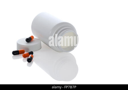 einige Pillen eine Farben schwarz und orange mit weißem Glas und eine Flasche mit Reflektion auf weißem Hintergrund Stockfoto