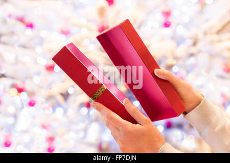 Frau öffnet ein rotes Geschenk vor einem Weihnachtsbaum Stockfoto