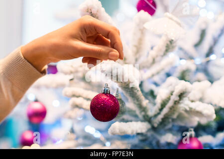Frau zu Hause dekorieren Weihnachtsbaum. Close-up Hände Stockfoto
