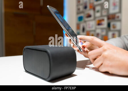 Frau verbinden Sie ihr Smartphone mit Lautsprecher. NFC, Bluetooth, kontaktlose Stockfoto