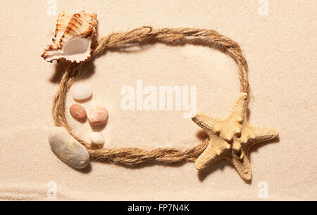 Ovalen Rahmen des Seils mit Seestern, leere Muschel und Steinen auf Sand. Sommer Strand Hintergrund. Ansicht von oben Stockfoto