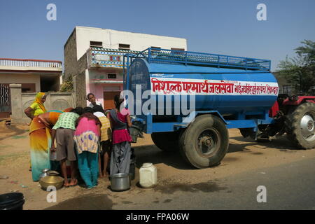 Rajasthan, Indien, versammeln sich Menschen auf einer öffentlichen Straße um eine Regierung Wasserversorgung Tanker ihre Behälter mit Wasser füllen Stockfoto