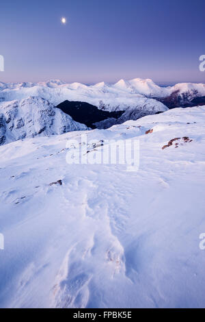 Ein Mond über den winterlichen Gipfeln der Arnisdale Berge bei Sonnenaufgang, Glenelg, von Sgurr Mhic Bharraich im Winter Stockfoto