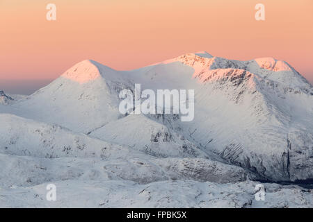 Die Gipfel auf Beinn Sgritheall werden rot, wenn sie von der aufgehenden Sonne, Glenelg, Schottland, von Sgurr Mhic Bharraich im Winter beleuchtet werden Stockfoto