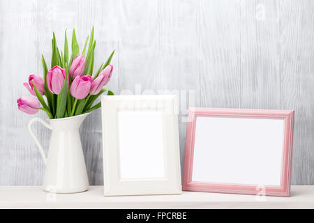 Frische rosa Tulpe Blumen Blumenstrauß und leere Bilderrahmen mit textfreiraum Regal vor Holzwand Stockfoto