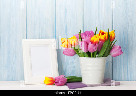 Frische Bunte Tulpen Blumen Bukett und leere Bilderrahmen mit textfreiraum Regal vor Holzwand Stockfoto