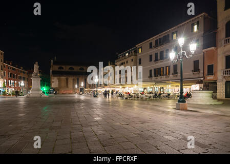 Menschen bevölkern Restaurants und Bars auf Santo Stefano Platz in Venedig in der Dämmerung an einem milden Frühlingstag Stockfoto