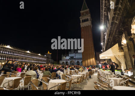 Menschen hören auf ein kleines Orchester bei einem Abendkonzert im Café "Caffe Florian" auf dem St. Marks Platz in Venedig Stockfoto