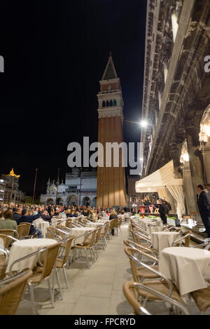 Menschen hören auf ein kleines Orchester bei einem Abendkonzert im Café "Caffe Florian" auf dem St. Marks Platz in Venedig Stockfoto