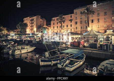 Kleine hölzerne Fischerboote vertäut im Hafen von Ajaccio, die Hauptstadt der Insel Korsika, Frankreich. Gewöhnliche Menschen gehen im küstennahen str Stockfoto