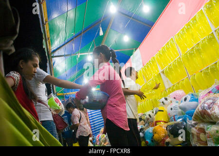 Eine Frau arbeitet auf ein Arcade-Spiel, wo Menschen werfen Darts auf Ballons an einem Strassenfest in Kampong Cham, Kambodscha. Stockfoto