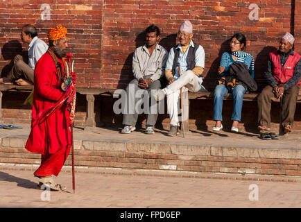 Nepal, Patan.  Ein Hindu Sadhu (Heiliger) geht es vorbei an Männer und eine Frau ruht auf Bank am Durbar Square. Stockfoto
