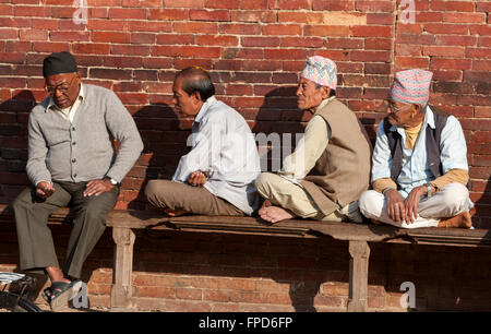 Nepal, Patan.  Vier nepalesische Männer sitzen auf der Bank am Durbar Square. Stockfoto