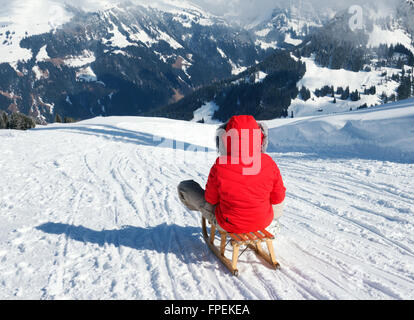 Eine junge Frau, Rodeln in den Schweizer Alpen im Urlaub, am Lenk, Kanton Bern, Schweiz-Europa Stockfoto