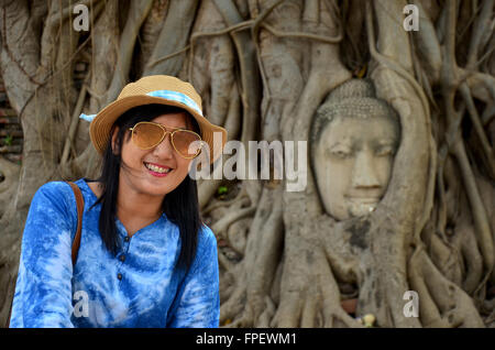 Thai Frau Porträt und nehmen Foto mit Stein Kopf des Buddha im Stamm Baum des Wat Mahathat in Ayutthaya, Thailand Stockfoto