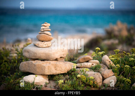 Zen-Raum. Steinen. Ses Illetes Strand, Balearen, Formentera, Spanien. Hintergrundbeleuchtung in den Sonnenuntergang mit Steinen mit verschiedenen Formen. "Die Flut" ("La Riada"), ein einzigartiger Raum mit Steinen von den deutschen Johannes Schultz gebaut. Stockfoto