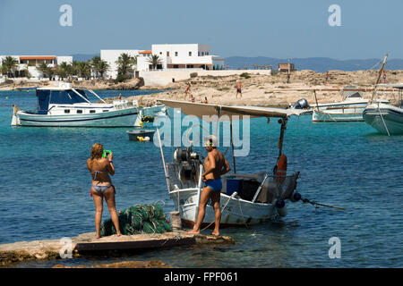 ELS Pujols Strand auf Formentera. Touristen, die aufgenommenen Bilder mit der traditionellen Fischerei Boot in Sommertag. Llaüt. Stockfoto