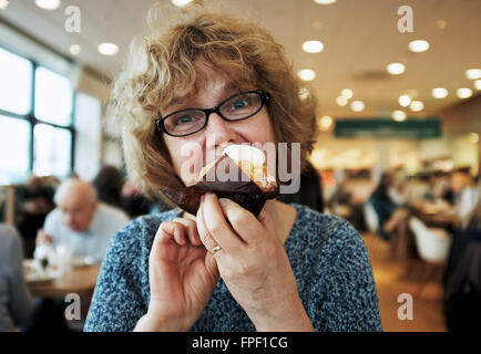 Mittlere gealterte Frau genießen ein eine Tasse Biskuit und Creme in einem Café Stockfoto