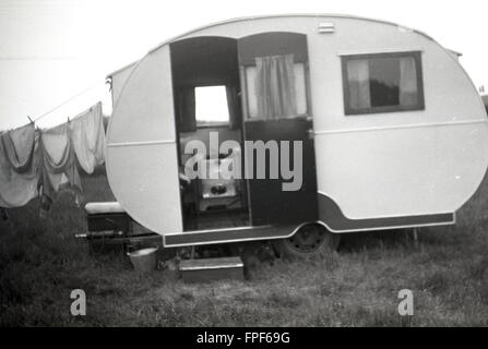 1950er Jahre historische, kleinen Liegeplatz-Karawane von der Ära in Feld mit Tür geparkt öffnen und waschen in Zeile angehängt. Stockfoto