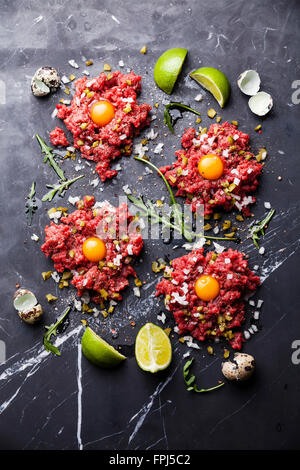 Beefsteak-Tatar mit Gewürzgurken und Zwiebeln auf dunklem Marmor Stockfoto