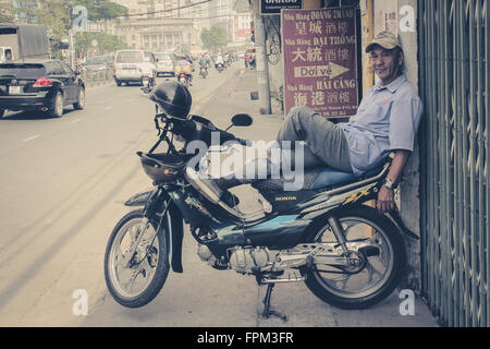 Saigon, Vietnam - 17. Januar 2014: Porträt eines Mannes entspannend auf seinem Roller / Motorrad. Saigon ist als Motorrad-Stadt bekannt. Stockfoto