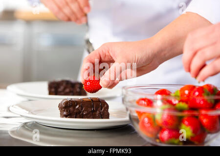 Köche schmückt Dessert Kuchen mit Schokoladensauce in Küche Stockfoto