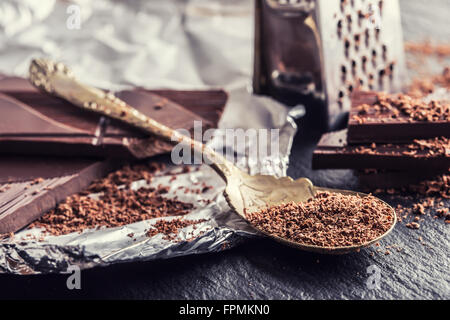 Schokolade. Schwarze Schokolade. Ein paar Würfel von schwarzer Schokolade. Schokolade Tafeln von geriebener Schokolade Pulver verschüttet. Kaffeebohnen. Stockfoto