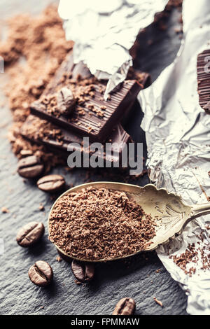 Schokolade. Schwarze Schokolade. Ein paar Würfel von schwarzer Schokolade. Schokolade Tafeln von geriebener Schokolade Pulver verschüttet. Kaffeebohnen. Stockfoto